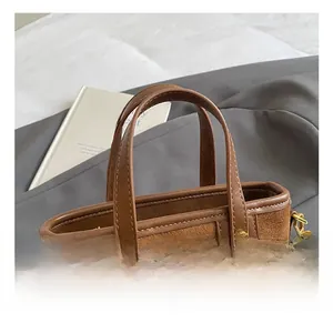 Detail of brown vintage bucket bag with leather stitching and gold metal rivets