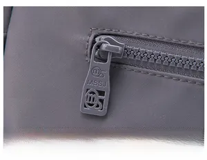 Detailed close-up of the smooth metal zipper and durable nylon fabric on a grey bag