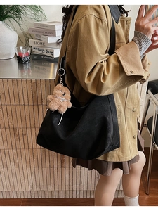 Dettaglio della borsa Hobo in pelle nera con un ciondolo a forma di orsetto di peluche