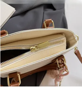 Close-up of smooth gold zipper and crocodile pattern on the beige bucket bag