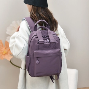 Detail view of a purple nylon backpack showing multi-pocket structure and logo detail
