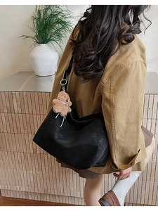 Vista dettagliata di una borsa tote in pelle nera con un simpatico ciondolo a orsetto