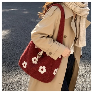 Detail of red plush knit tote bag with white flower patterns and wooden toggle closure