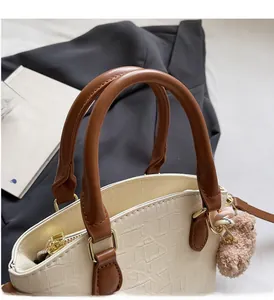 Detail of cream crocodile embossed bucket bag with brown handle and plush bear charm