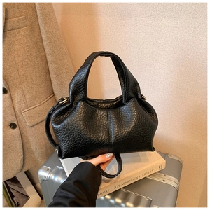 Detail of black pebbled leather cloud bag with gold hardware and adjustable strap