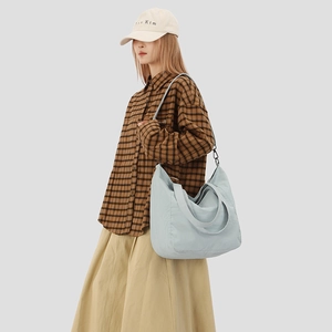 Detail of light blue crossbody bag featuring adjustable straps and large capacity