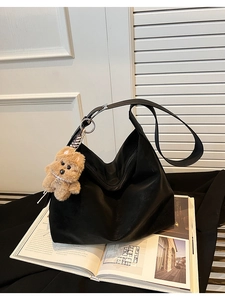 Dettaglio della borsa hobo in ecopelle nera con ciondolo a forma di cane di peluche nero