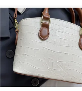 Detail of cream crocodile embossed leather bucket bag with brown trim and gold hardware