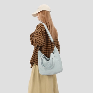 Detailed view of light blue tote bag on model showing woven handles and shoulder strap