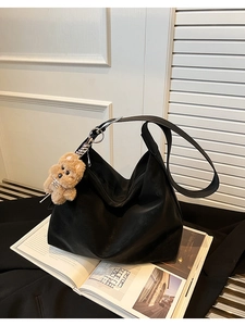 Dettaglio della borsa hobo in pelle nera opaca con ciondolo a forma di orsetto marrone
