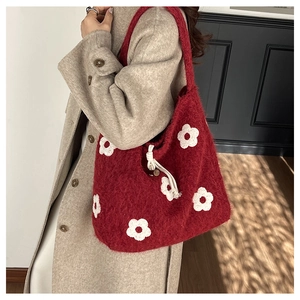 Detail of red fuzzy tote bag with white flower patterns and woven drawstring accents