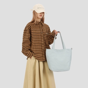 Light blue large capacity tote bag with front pocket shown on a female model
