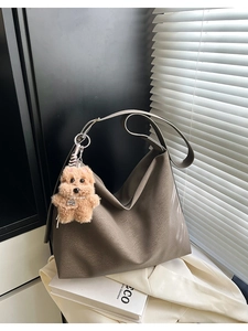 Dettaglio della borsa tote in pelle taupe con ciondolo a forma di cane in peluche marrone