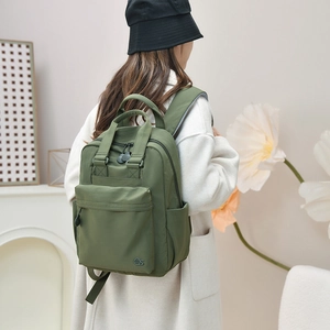 Olive green nylon backpack detail showing reinforced handles and large multi-pocket design