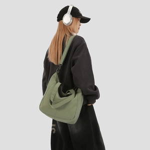 Detail view of olive green canvas tote bag with wide strap on model in streetwear style