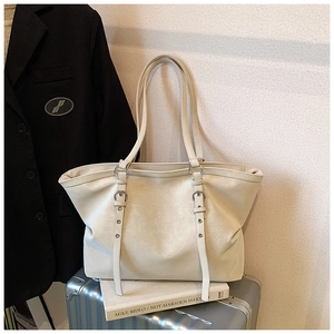 Detail of a beige textured faux leather tote bag on a silver suitcase with a blazer