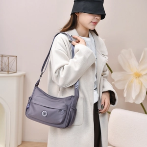 Waterproof purple nylon bag with woven strap shown on a model in a casual setting
