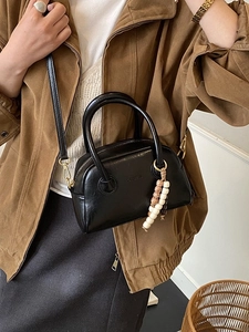 Retro black leather boston bag with top handles and a bohemian beaded charm