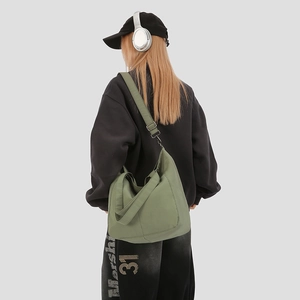 Detail of an olive green canvas crossbody bag with adjustable strap and large capacity