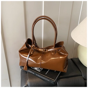 Close-up of vintage brown glossy leather shoulder bag with sleek metal buckle strap