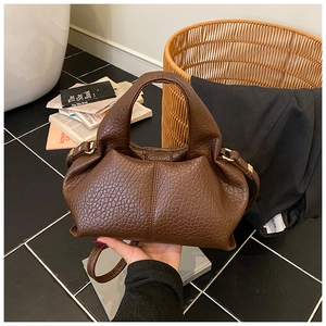 Close-up of deep brown lychee texture leather handbag with gold metal ring detail