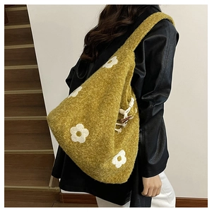 Detail of plush tote bag with flower embroidery, wooden toggle, and woven rope closure