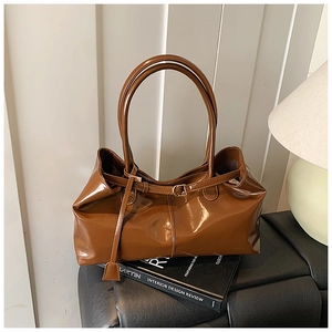 Detailed view of deep brown patent leather tote with shiny mirror finish and gold buckle