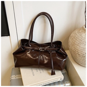 Detail of dark brown glossy leather tote bag with vintage metal buckle and slim straps