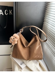 Dettaglio ravvicinato della borsa tote in pelle marrone con ciondolo a orsetto