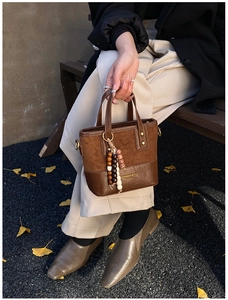 Detail of vintage brown suede crossbody bag with decorative wooden beads and branding