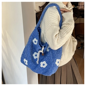 Detail of blue plush tote bag with white flower patterns and drawstring closure
