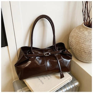 Detail of dark brown glossy leather tote bag with long straps on vintage suitcase
