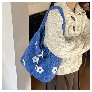 Detail of blue plush tote bag featuring white floral patterns and drawstring closure