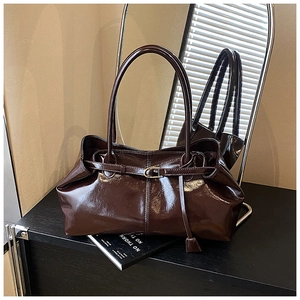 Macro shot of dark brown glossy patent leather tote bag with elegant buckle detailing