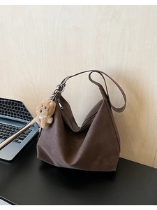 Dettaglio della borsa tote in pelle marrone con ciondolo a forma di orsetto morbido