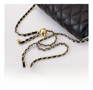 Détail d'un sac bandoulière en cuir noir matelassé avec chaîne dorée à bille ajustable