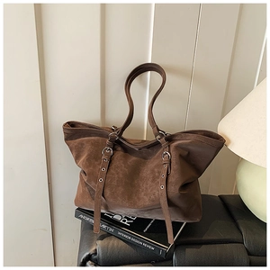 Détail d'un grand sac cabas marron foncé montrant le cuir vintage et les boucles argentées
