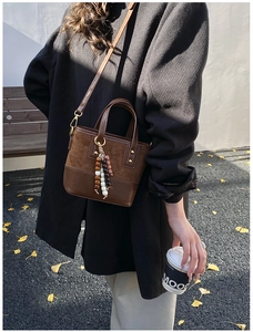 Detail of vintage brown suede tote with wooden beads tassel in autumn outdoor setting