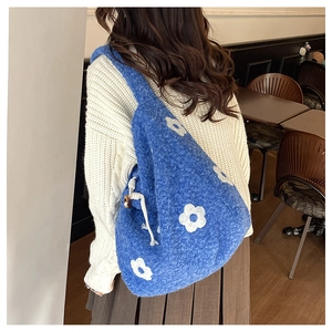 Detail of dark blue plush tote with white floral patterns and wooden charm accents