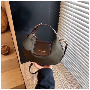Close-up of olive green matte hobo bag with gold logo and wooden background decor