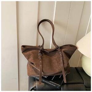 Détail d'un grand sac cabas marron vintage avec boucles latérales sur cuir noir