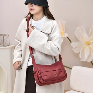 Detail view of burgundy nylon crossbody bag featuring wide jacquard shoulder strap