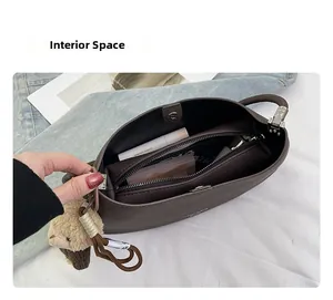 Close-up of brown pebbled leather handbag interior with compartments and plush sheep charm