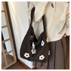 Detail of coffee brown knit tote bag featuring white floral patches and toggle button