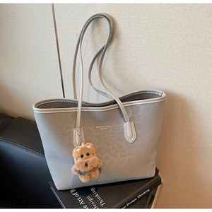 Detail of light grey leopard print tote bag with plush bear charm and MIKAXXI brand logo