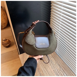 Detail of olive green suede hobo bag with dark brown leather flap and heart charm