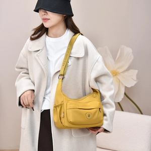 Detail of water-resistant yellow nylon crossbody bag featuring side elastic pockets