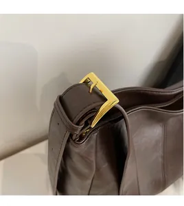 Detail of dark brown glossy leather bag showing the golden buckle and shoulder strap