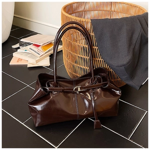 Macro detail of glossy dark brown patent leather tote with metallic buckle and slim straps