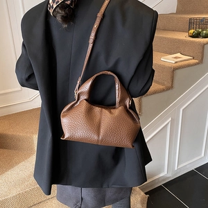Detail of a brown lychee-textured dumpling bag shown on a black blazer for chic styling